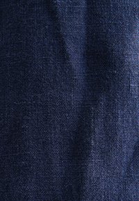 Tissu texturé bleu foncé avec un motif tissé, présentant un léger éclat et des fibres naturelles, créant une apparence de couleur riche et profonde.