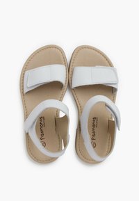 Sandales en cuir blanc avec deux sangles réglables en velcro, semelle beige et détails cousus. Design ouvert à l'avant avec une semelle plate.