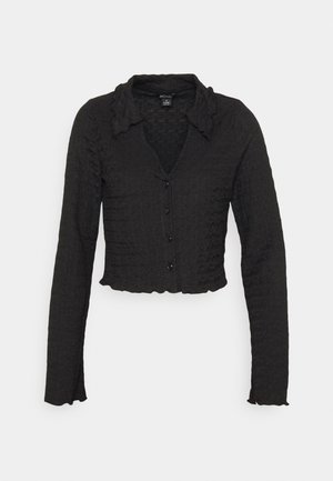 Zwarte cropped cardigan met lange mouwen, knopen aan de voorkant, gestructureerde stof, licht gerimpelde kraag en zoom, weergegeven op een witte achtergrond.
