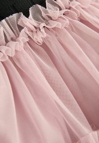 Tessuto di tulle arricciato rosa chiaro con una fine trama a rete, attaccato a una fascia elastica nera.
