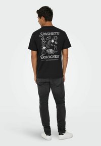 Camiseta negra con impresión gráfica blanca de espaguetis e ingredientes, con el texto "Spaghetti Bolognese" en la parte posterior. Corte clásico.