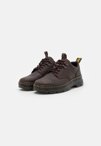 Dark brown lace-up shoes with a smooth leather upper, yellow stitching along the sole, and a textured rubber sole for grip.