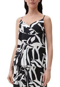 Haut sans manches noir et blanc avec un col en V, présentant un imprimé audacieux de feuilles abstraites sur un tissu texturé. Bretelles fines ajustables.