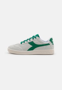 Grå semsket sneakers med grønne accenter, har en glatt overflate, snøring og en hvit gummisåle. Side logo detalj er til stede.