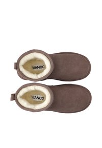 Stivali alla caviglia in suede marrone con una morbida fodera in pelliccia crema, punta tonda e linguetta ad anello sul retro. Logo "BIANCO" visibile all'interno.