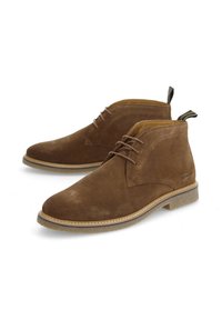 Bottines en daim marron avec un bout arrondi, semelle en caoutchouc plate et lacets marron. Équipées d'une languette à l'arrière et de détails de couture subtils.