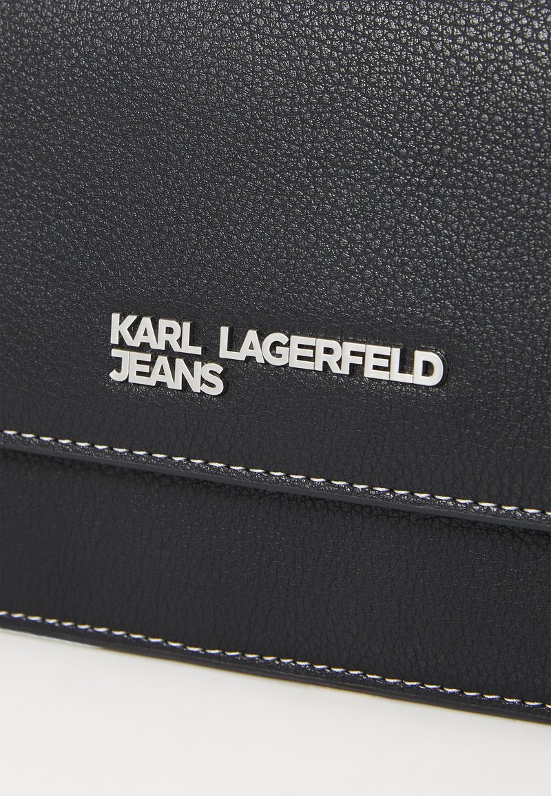 Pelle nera texture con cuciture bianche; presenta un logo argento con la scritta "KARL LAGERFELD JEANS" impressa sulla parte anteriore.