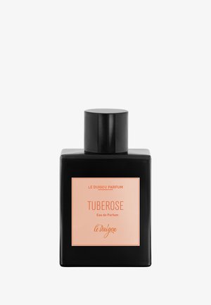 Schwarze rechteckige Parfümflasche mit einem Pfirsich-Etikett mit der Aufschrift "TUBEROSE Eau de Parfum" von Le Duigou Parfum und einem zylindrischen schwarzen Deckel.