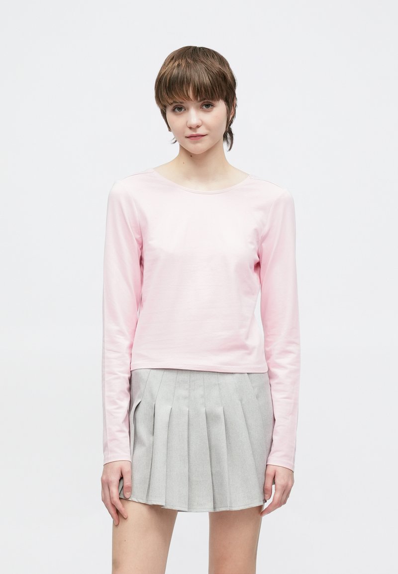 Ροζ μπλούζα με μακριά μανίκια από απαλό ύφασμα, συνδυασμένη με φούστα σε γκρι χρώμα με πιέτες. Απλός σχεδιασμός με στρογγυλή λαιμόκοψη και εφαρμοστή γραμμή.