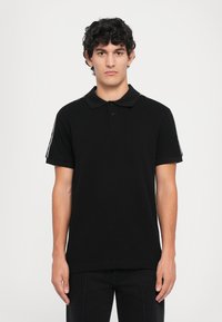 Black polo shirt with a collared neckline, short sleeves, and two-button placket. Features white accent stripes on the shoulders.