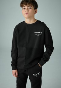 Svart sweatshirt- och byxset med en texturerad design, ribbade manschetter och "ALLSAINTS"-logga i vitt på bröstet och benet.