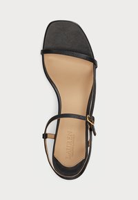 Must kolm rihmaga must nahast sandaal ruuduvarbaga, millel on kuldne kinnituse aksessuaar. Heledat tooni sisetald, millel on reljeefne logo ja sile pind.