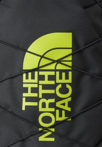 Svart stoffsekk med fremtredende gul logo. Har elastisk snordesign for utvidelse. Jevn tekstur med slitesterk konstruksjon.