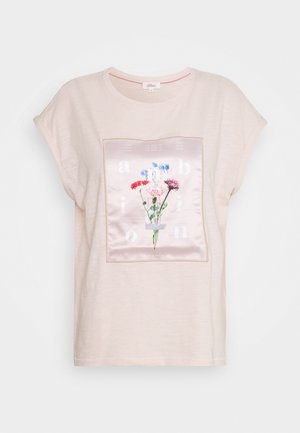 Camicia rosa chiaro a maniche corte con un pannello quadrato in raso che presenta fiori colorati e lettere bianche sul davanti.