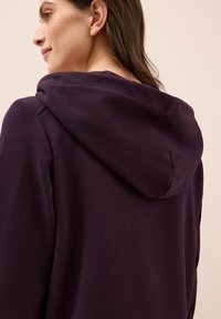 Felpa con cappuccio viola in tessuto strutturato e vestibilità rilassata, presenta un cappuccio prominente e una finitura liscia sul retro.