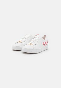 Baskets en cuir blanc avec une texture lisse, dotées d'un logo rose sur les côtés et d'accents en métal doré sur les lacets. Semelle en caoutchouc plate.