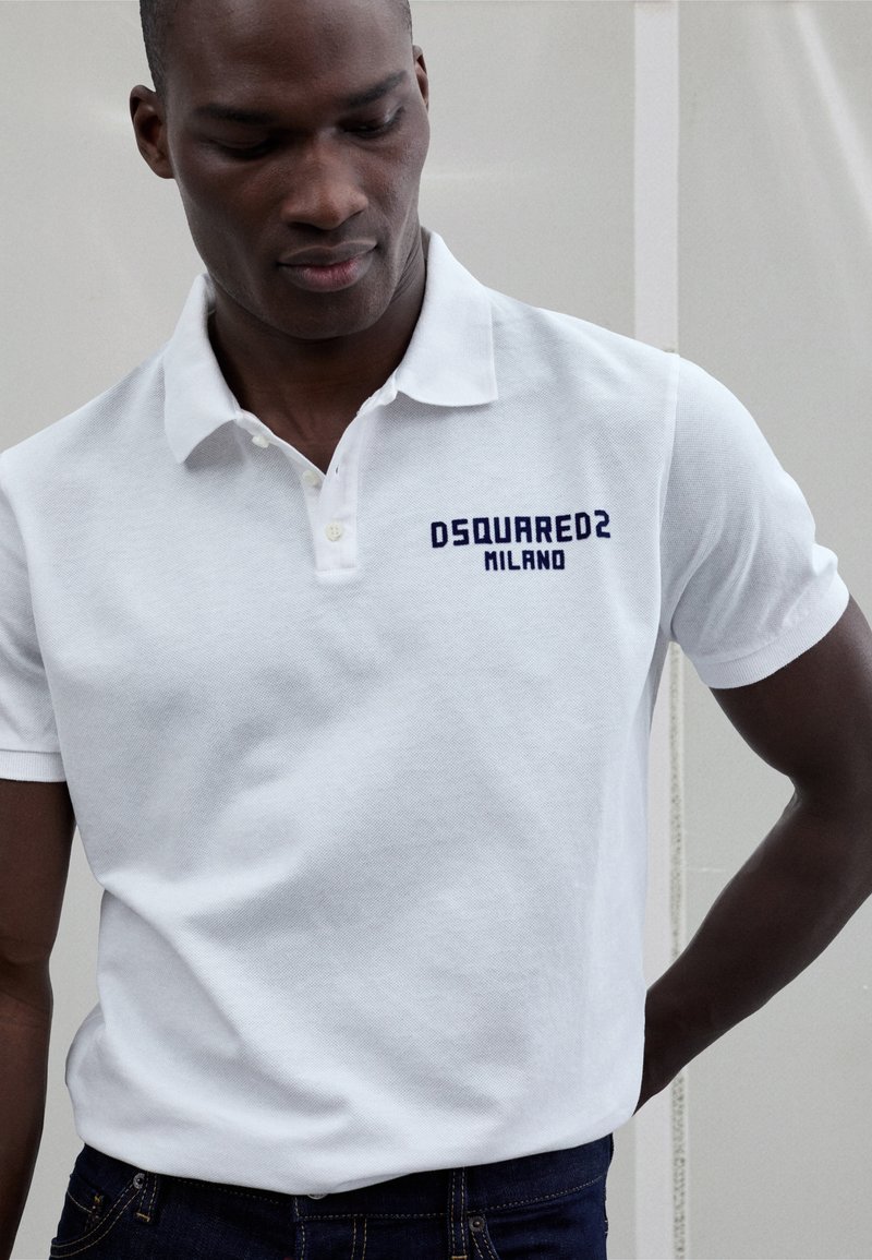 Fehér pamut póló texturált felülettel, bal oldali mellrészen tengerészkék "DSQUARED2 MILANO" logóval.