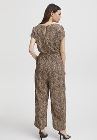 Jumpsuit con stampa leopardata in tonalità marroni, maniche corte, dettaglio con apertura a chiave sulla schiena, vita elastica, gamba larga e tessuto morbido.