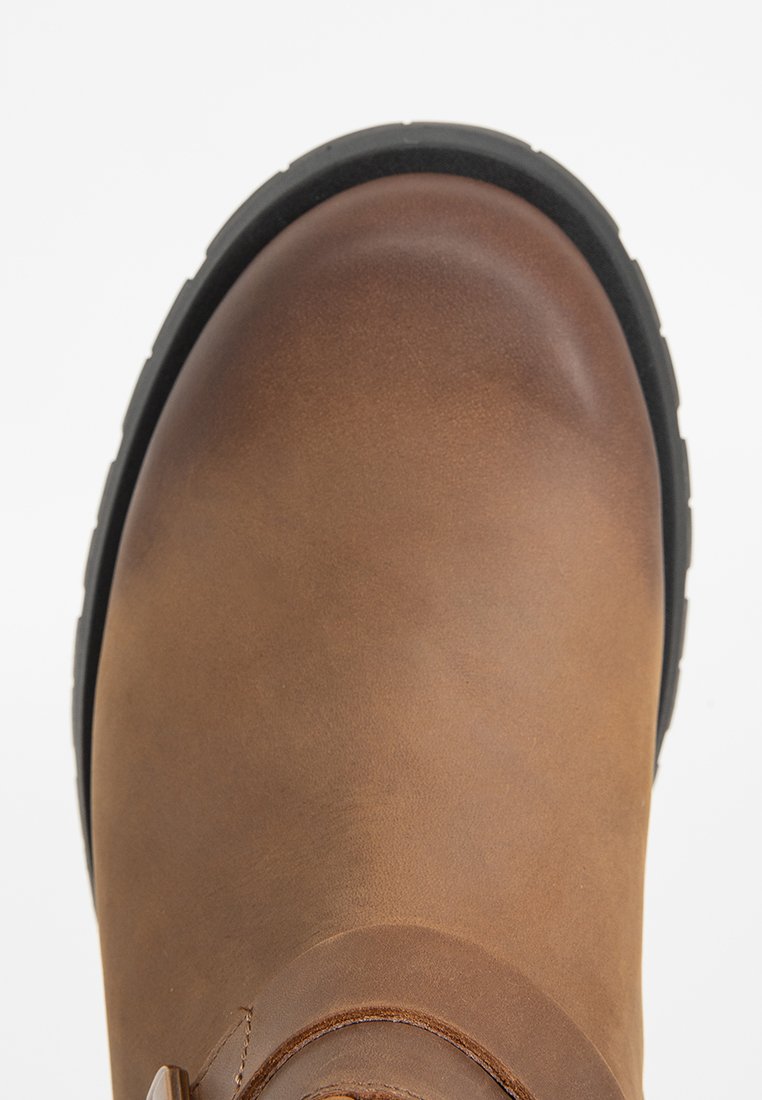 Botín de cuero marrón hasta el tobillo con puntera redondeada y superficie texturizada. Presenta una suela de goma negra y un sutil detalle de costura.