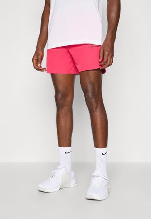 Lyserøde Nike Pro shorts med elastisk talje, parret med hvide Nike sko og sokker med et sort logo, mod en neutral baggrund.