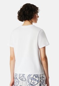 Weißes Baumwoll-T-Shirt mit Rundhalsausschnitt und kurzen Ärmeln, von hinten gezeigt. Glatte Textur und lockere Passform.