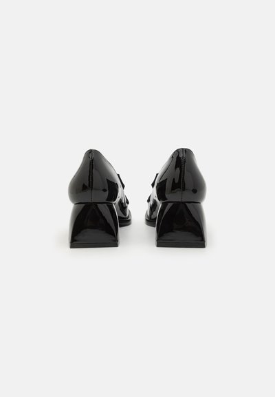 Patent black heels with a curved back, angular block heel, and smooth texture. Features a stitched detail along the back seam.