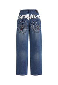 Dżinsy o luźnym kroju, z haftowanymi wzorami pajęczej sieci na tylnych kieszeniach oraz stylizowanym białym napisem nad paskiem.