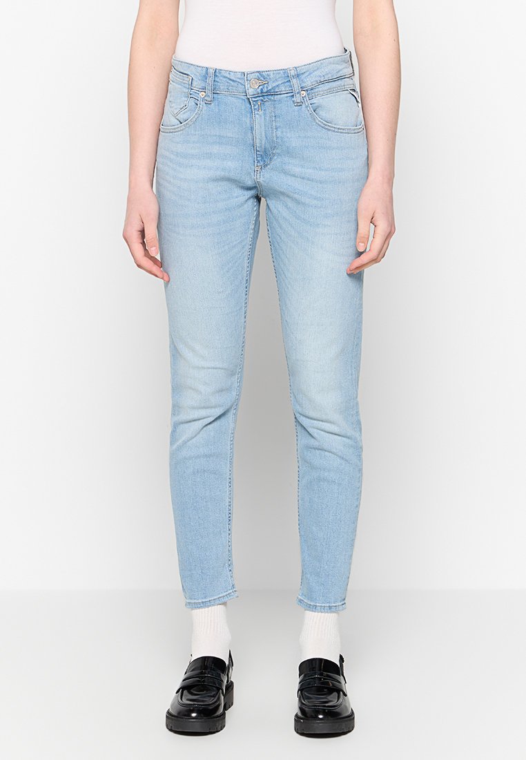 Lichtblauwe skinny jeans van denim met twee frontzakken, een rits, en een licht vervaagde afwerking. Draagt met zwarte schoenen en witte sokken.
