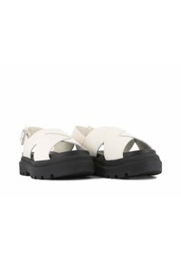 Sandali in similpelle bianca con cinturini incrociati e dettagli argentati. Sole spesso in gomma nera con suola anti-scivolo per una migliore presa. Chiusura con fibbia.