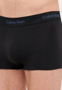 Μαύρο βαμβακερό σλιπ με λογότυπο Calvin Klein στη μαλακή ζώνη. Ο ύφασμα έχει απαλή υφή και εφαρμοστή γραμμή.