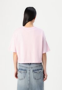 Lys rosa kortermet t-skjorte med rund hals og myk bomullstekstur. Kombinert med et denimskjørt med baklommer.