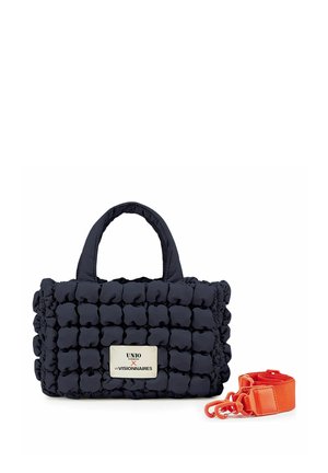 Kleine schwarze gesteppten Handtasche mit kurzen Griffen, einem weißen Etikett vorne und einem abnehmbaren, leuchtend orangefarbenen Schulterriemen daneben.