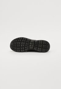 Zwarte sneakerzool met een gestructureerd patroon; voorzien van een rubberen grip voor grip; afgeronde neus en stevig gestructureerd ontwerp.