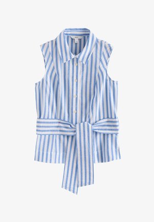 Femme portant une robe sans manches à rayures verticales bleu et blanc avec une ceinture nouée à la taille, les mains dans les poches, et un bracelet argenté au poignet droit.