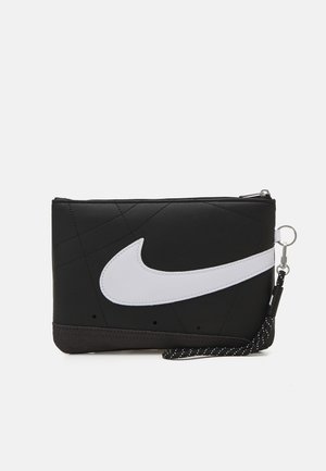 Bolsa de bolsillo sintética negra con un gran logo blanco de Nike, superficie texturizada, cierre de cremallera y correa desmontable con acentos en negro y blanco.