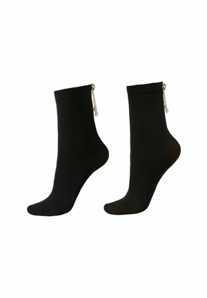 Sorte ankelstrømper med en glat tekstur, der har sølvkædeaccent og små dekorative perler fastgjort ved kanten.