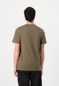 Tricou scurt cu mânecă scurtă de culoare verde măsliniu, fabricat din bumbac moale, având guler rotund și un croi lejer. Design simplu, fără modele vizibile.