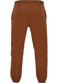 Hnedé jogger nohavice vyrobené z mäkkého materiálu, s elastickým pásom, bočnými vreckami a elastickými manžetami na členkoch.