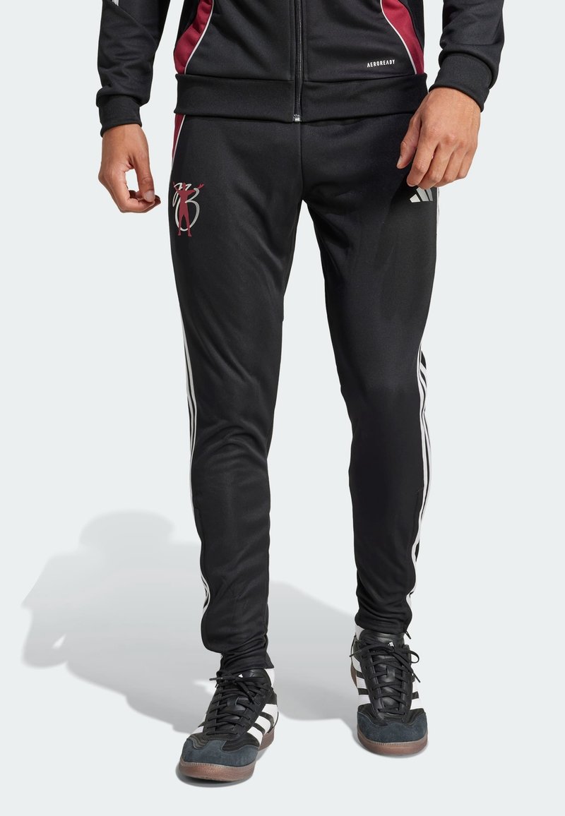 Pantalones deportivos negros con un diseño ajustado, que presentan franjas blancas a lo largo de los lados y un logotipo granate en la parte frontal. Tejido suave y flexible.
