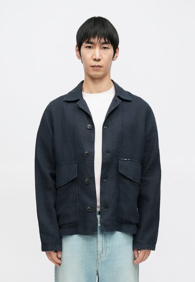 Marineblaue Jacke aus strukturiertem Stoff, mit durchgehendem Knopfverschluss, zwei großen Fronttaschen und klassischem Kragen.
