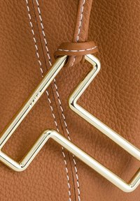 Borsa a mano in pelle marrone con una sfarzosa ferramenta metallica dorata in una design a zigzag, arricchita da dettagli di cucitura bianca a contrasto.