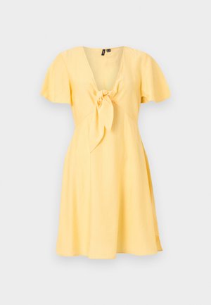 Κίτρινο φόρεμα με κοντά μανίκια, V-λαιμόκοψη και λεπτομέρεια δεσίματος μπροστά, με φαρδιά φούστα, εμφανίζεται σε απλό φωτεινό φόντο.