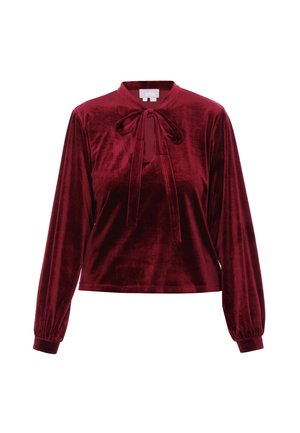Bordeaux fluwelen blouse met een hoge hals, lange uitpuilende mouwen en een strikdetail bij de kraag. Soepele textuur en een iets verkorte pasvorm.