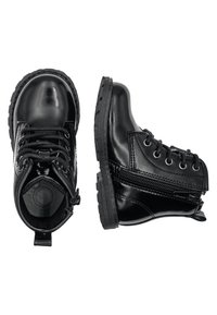 Botas de tobillo negras y brillantes con cordones en el frente y cremallera lateral. Suelas de goma con agarre texturizado. Punta redondeada y acentos cosidos.