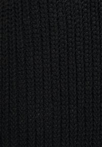 Černá pletená tkanina s žebrovanou strukturou, s těsně tkanými vlákny pro hrubý vzhled. Žádné vzory nebo akcenty nejsou viditelné.