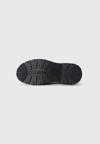 Black rubber shoe sole featuring deep tread patterns, with a logo embossed in the center. Smooth texture with reinforced heel areas.