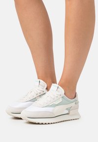 Baskets légères en blanc et vert menthe, avec des matériaux en maille et en daim, des accents texturés et une semelle rembourrée.