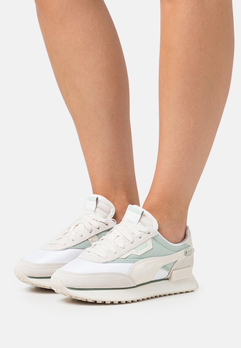 Baskets légères en blanc et vert menthe, avec des matériaux en maille et en daim, des accents texturés et une semelle rembourrée.