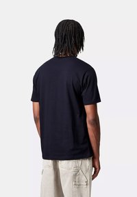 T-shirt nera a maniche corte con scollo rotondo, realizzata in tessuto morbido, caratterizzata da un design pulito e minimalista, senza loghi o pattern visibili.