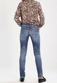 Blå slitna skinnyjeans i denim med medelhög midja, ljus blekning och en mjuk textur. Har fem fickor och en sydd läderlogotyp.